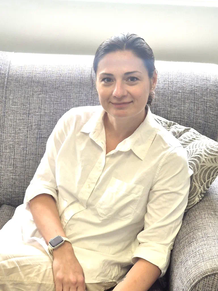 Woman in white shirt seated on grey sofa