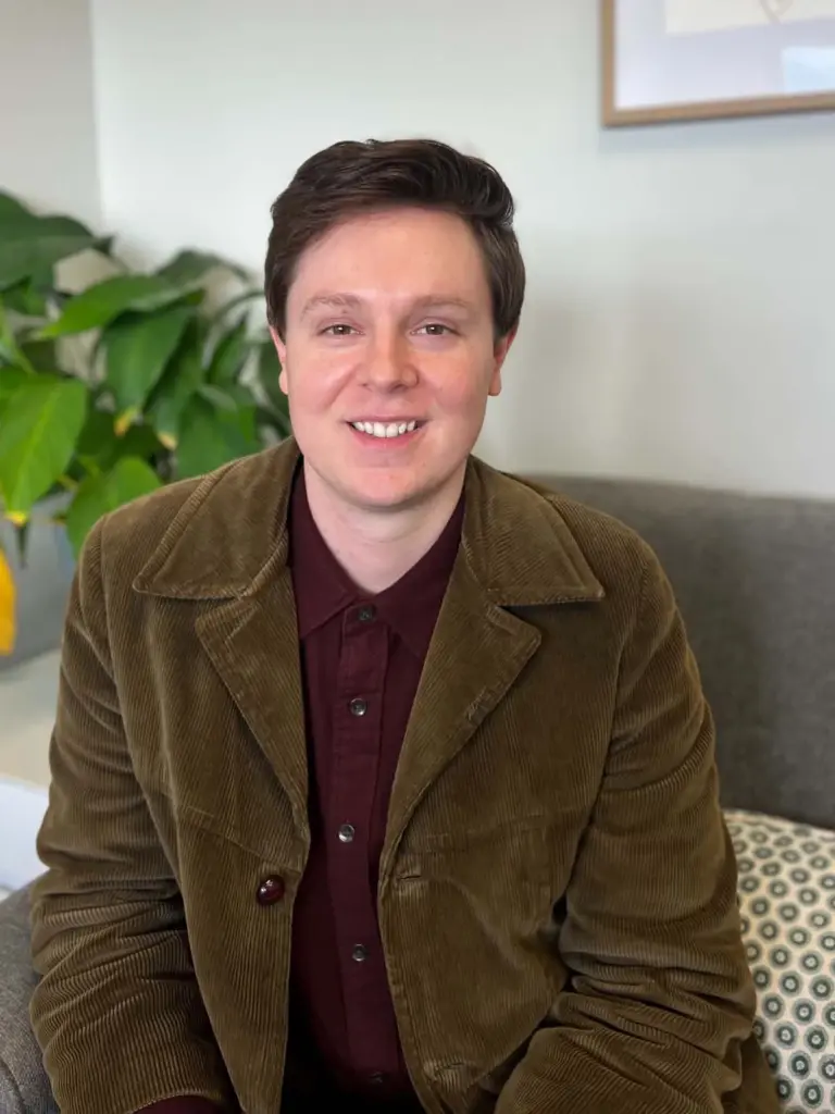 Smiling person in brown jacket indoors